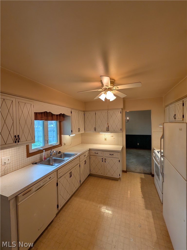 1161 Gulf Road Elyria, OH 44035 - Photo 11 of 34 Kitchen featuring white cabinetry with diamond-patterned door details, light countertops, and a double basin sink beneath a window