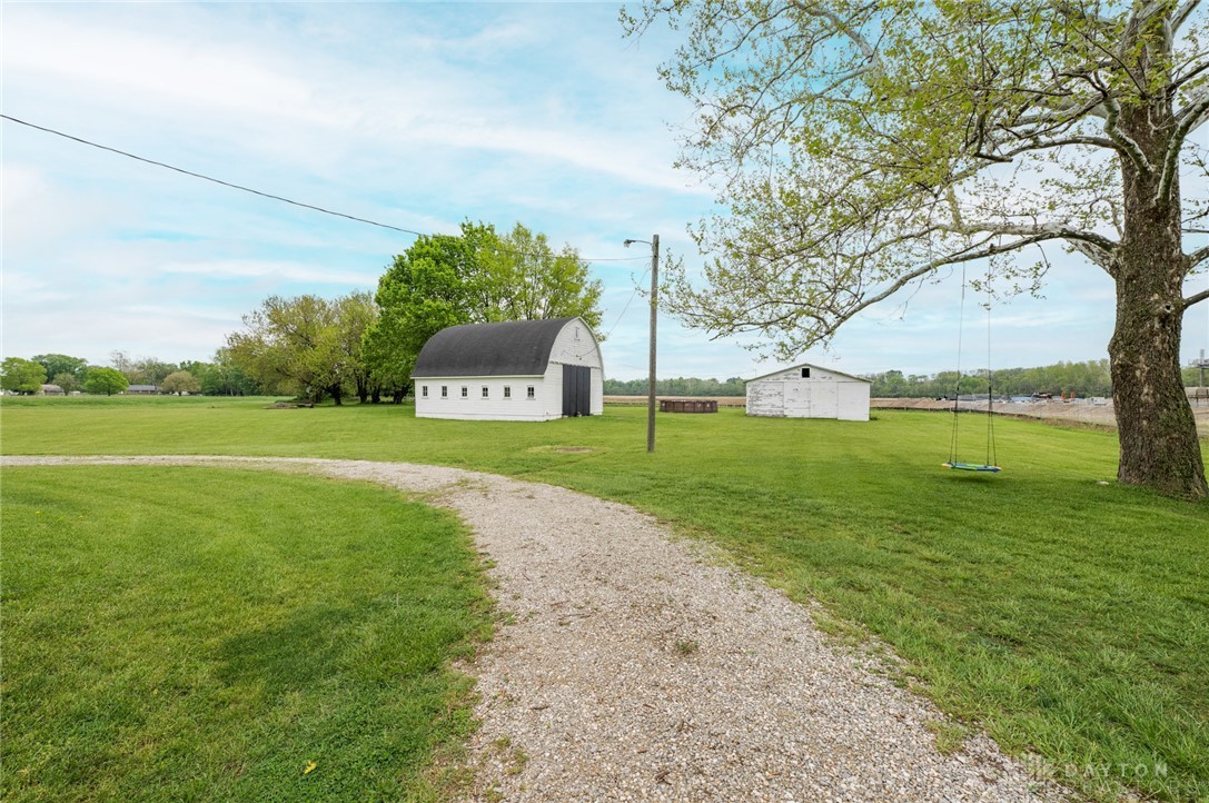 190 Swailes Road Troy, OH 45373 - Photo 63 of 82 This expansive rural property offers a private drive leading to two charming outbuildings amidst lush green fields.