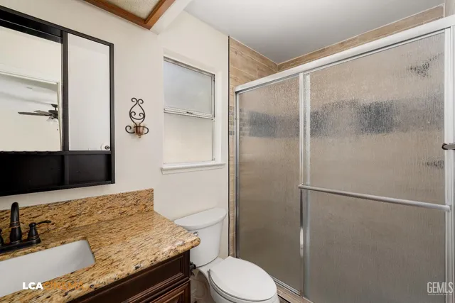 a bathroom with a granite countertop sink toilet and shower