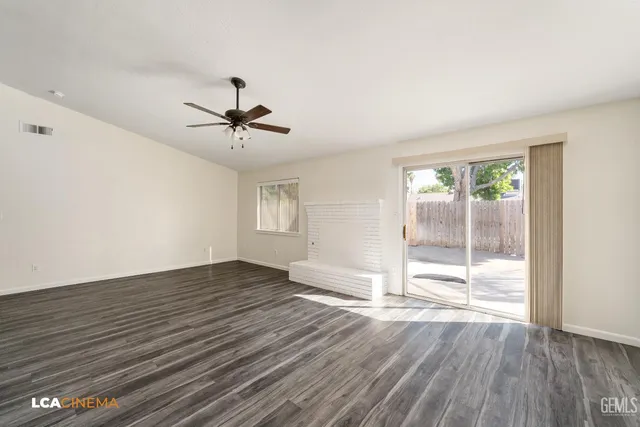 an empty room with wooden floor and chandelier fan