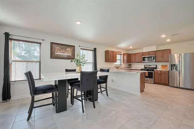 a kitchen with a dining table chairs and refrigerator