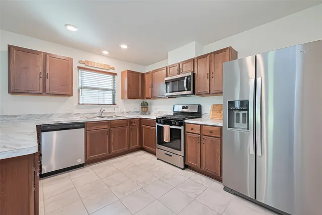 a kitchen with stainless steel appliances granite countertop a refrigerator sink and stove