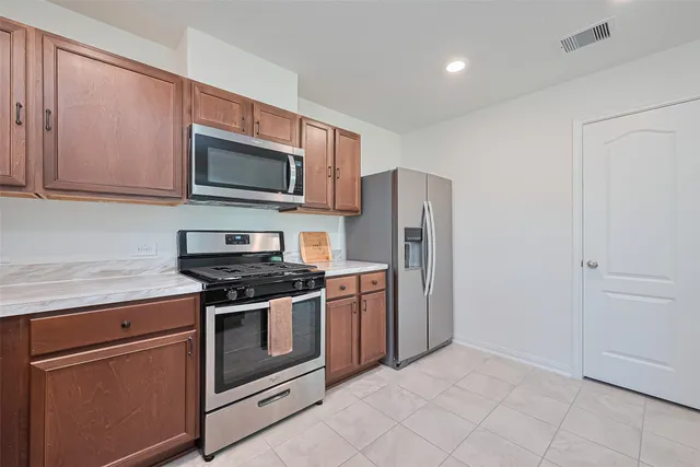 a kitchen with stainless steel appliances granite countertop a stove a microwave and a refrigerator