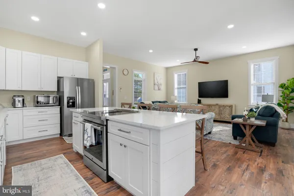 a living room with stainless steel appliances kitchen island furniture and a flat screen tv