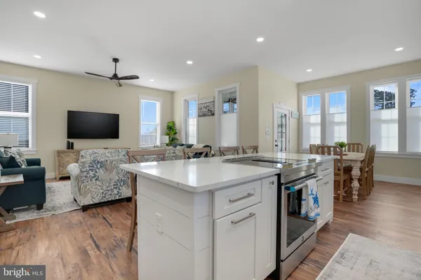 a view of living room kitchen with stainless steel appliances kitchen island granite countertop a stove and a sink