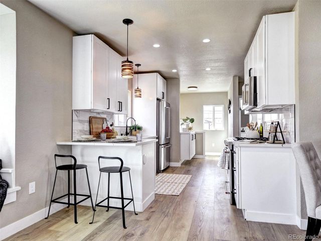 a kitchen with refrigerator a stove and wooden floor