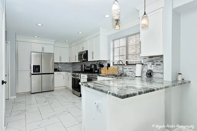 a kitchen with stainless steel appliances granite countertop a sink a stove a refrigerator cabinets and a window