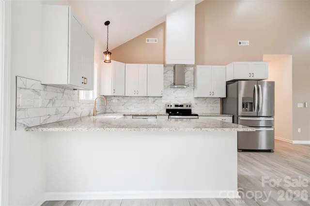 a kitchen with stainless steel appliances a refrigerator a stove a sink and white cabinets