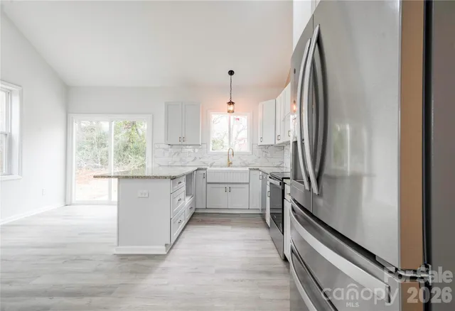 a large white kitchen with sink a window and stainless steel appliances
