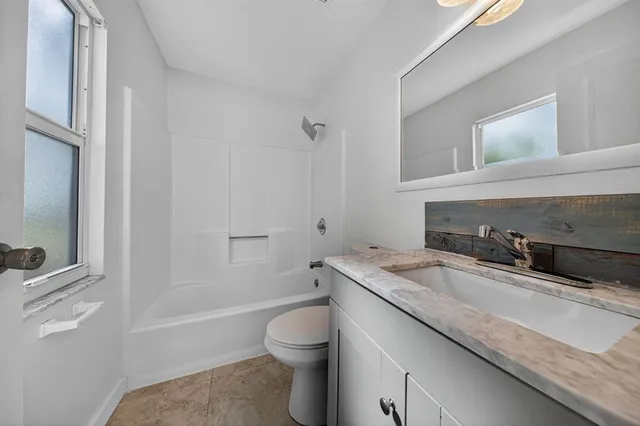 a bathroom with a granite countertop toilet sink and mirror