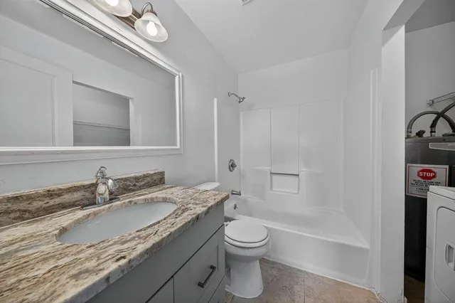 a bathroom with a granite countertop sink a toilet and a mirror