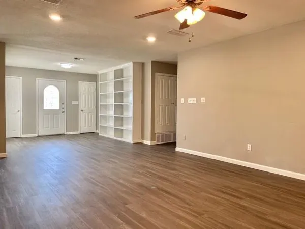 a view of an empty room with a window and wooden floor