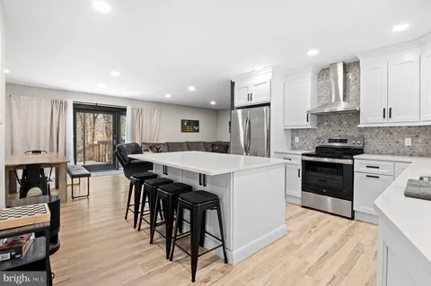 a kitchen with stainless steel appliances a stove a sink a refrigerator white cabinets and wooden floor