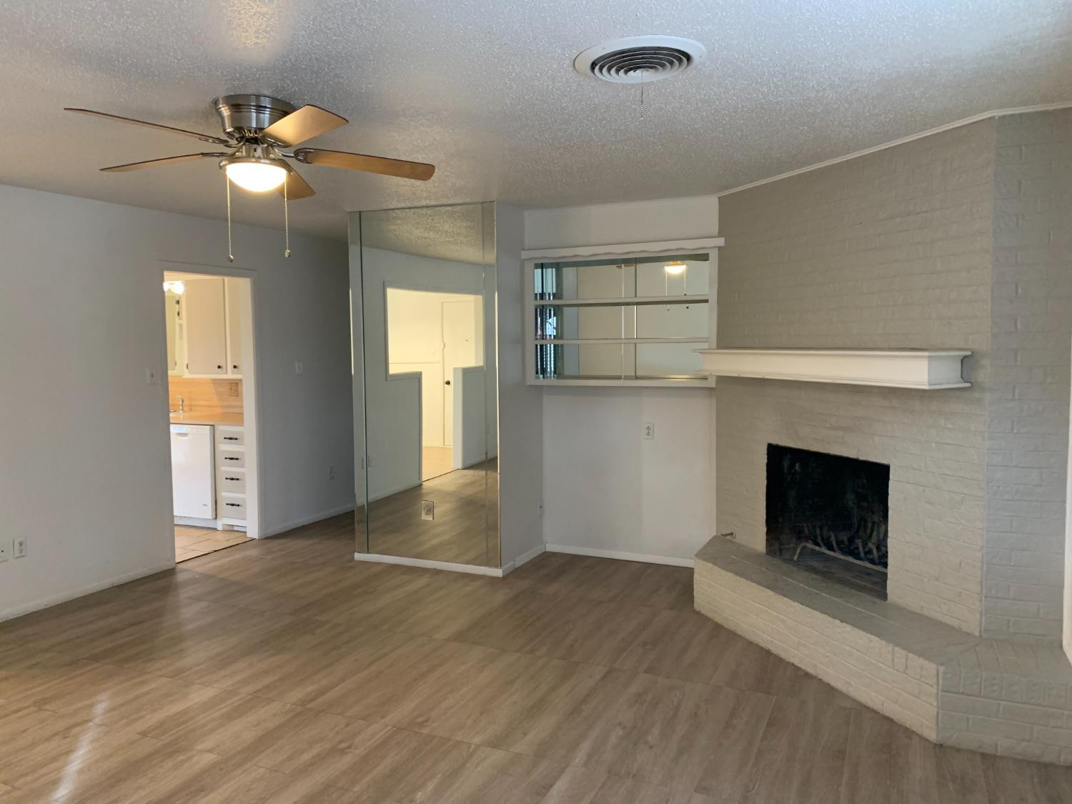 4316 58th Street, Unit B Lubbock, TX 79413 - Photo 13 of 30 a view of an empty room with wooden floor and a fireplace