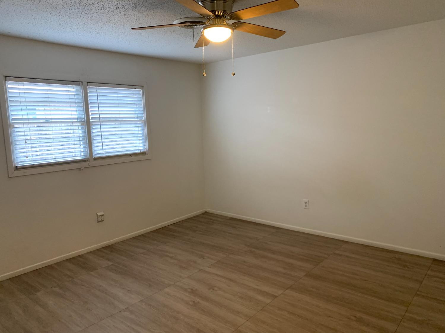 4316 58th Street, Unit B Lubbock, TX 79413 - Photo 5 of 30 an empty room with wooden floor and windows