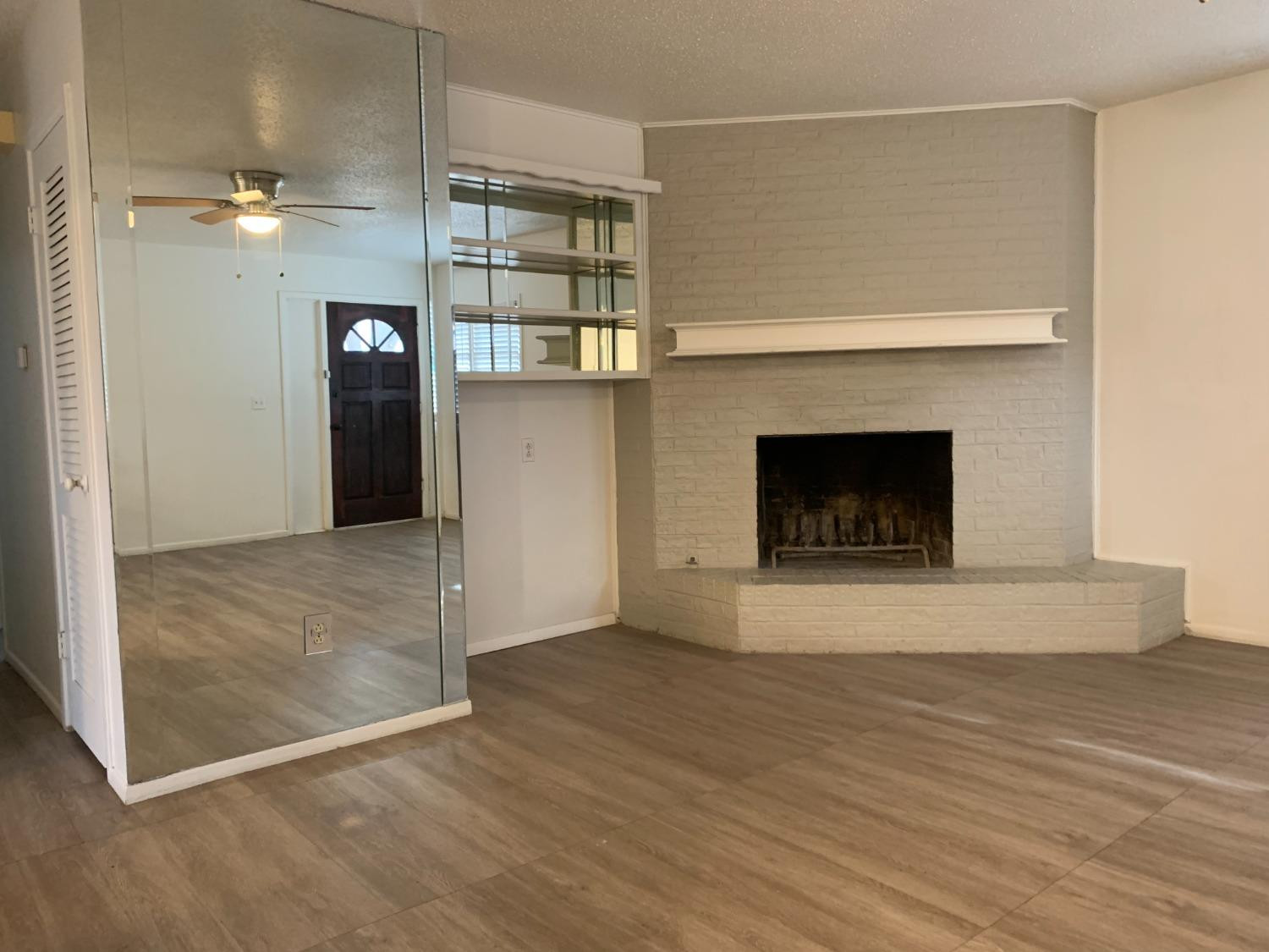 4316 58th Street, Unit B Lubbock, TX 79413 - Photo 10 of 30 a view of an empty room with wooden floor and a fireplace