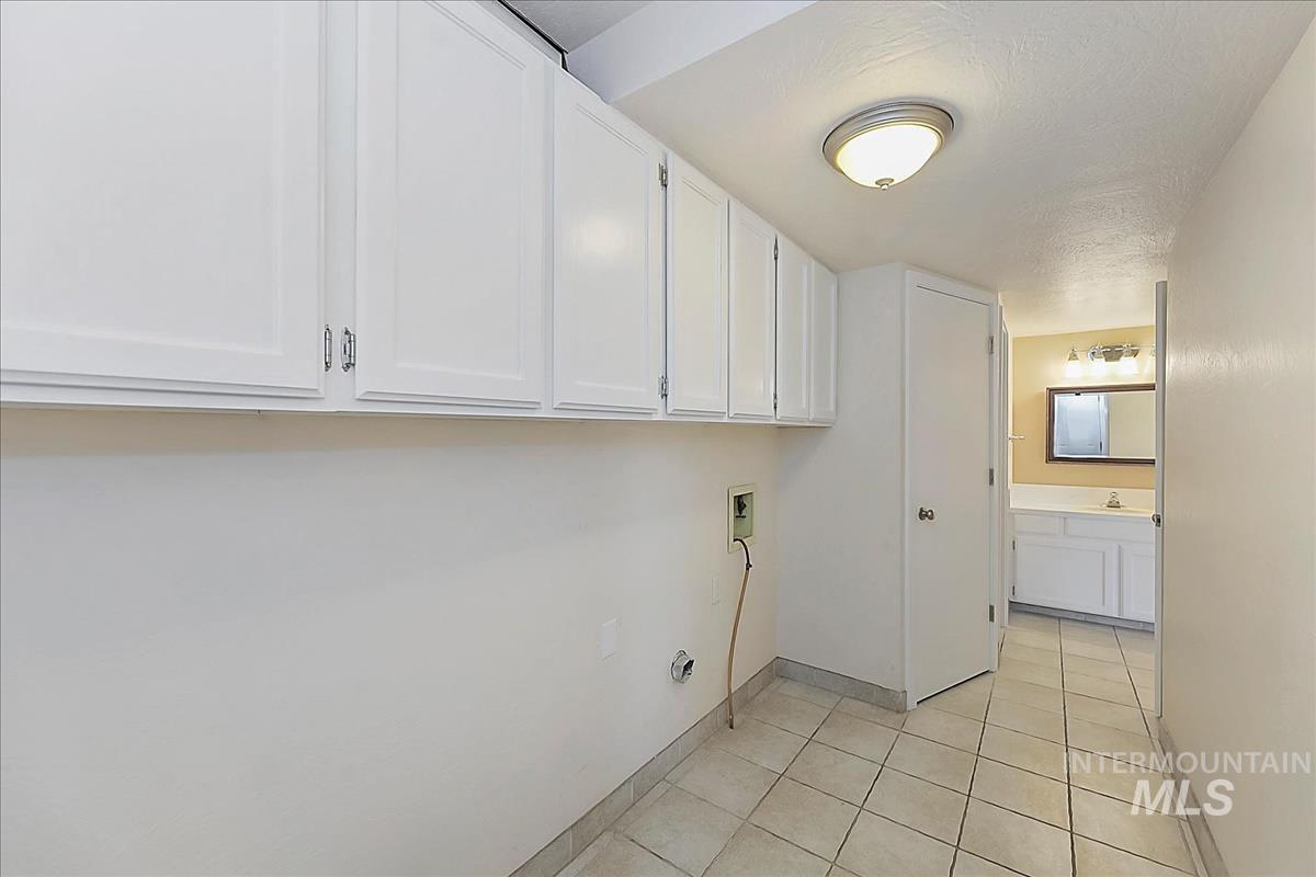 2804 West Sunrise Rim Road Boise, ID 83705 - Photo 11 of 50 Laundry area featuring upper white cabinetry, tile flooring, and flush-mount lighting