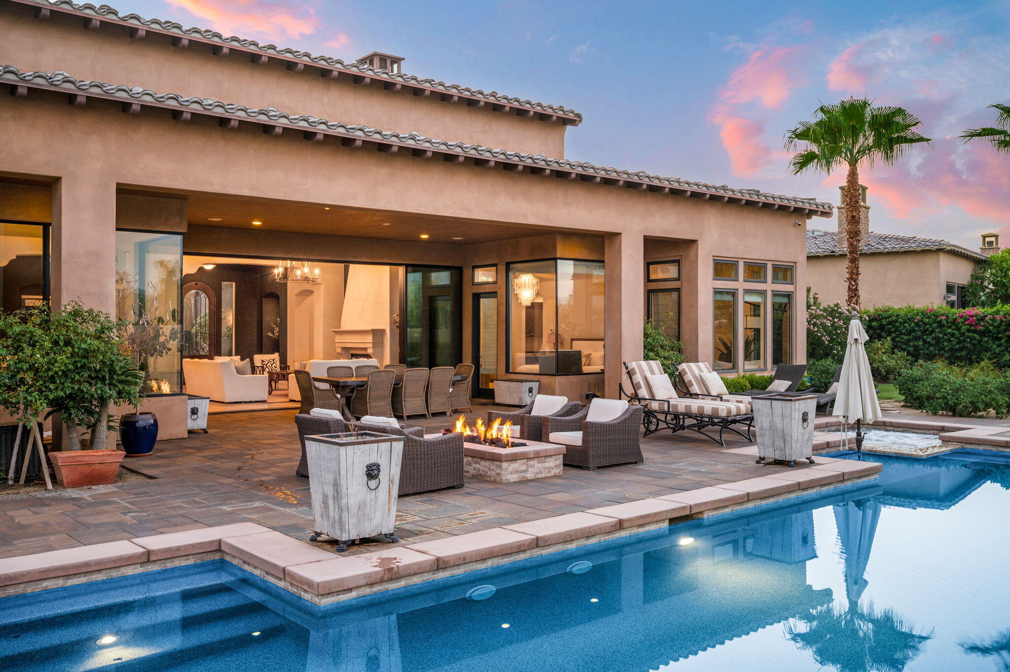 54360 Alysheba Drive La Quinta, CA 92253 - Photo 66 of 68 a dining hall with couches a flat tv screen and potted plants with wooden floor