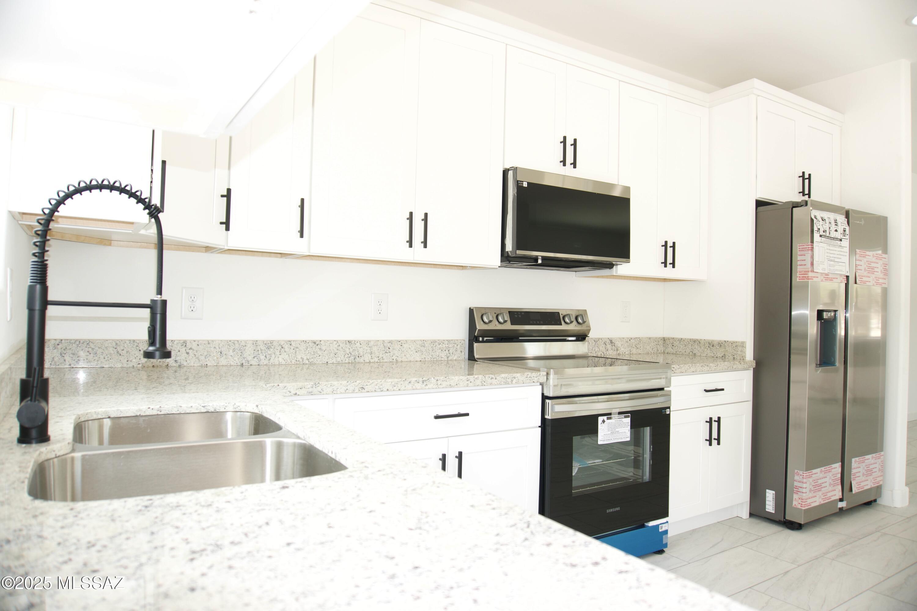 126 Alemania Court Rio Rico, AZ 85648 - Photo 14 of 31 a kitchen with stainless steel appliances kitchen island a sink stove and refrigerator