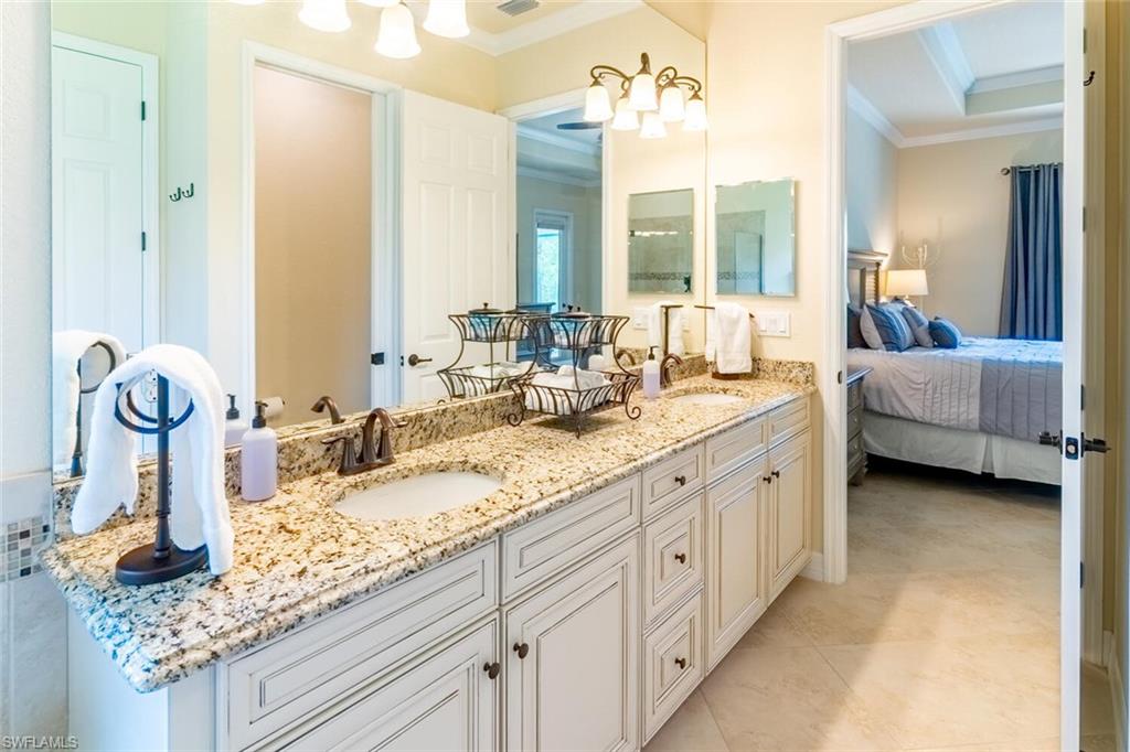 9372 Vercelli Court Naples, FL 34113 - Photo 23 of 50 Bathroom with crown molding, a raised ceiling, dual vanity, and tile patterned flooring