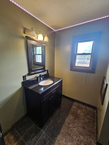 an empty room with chandelier fan and windows