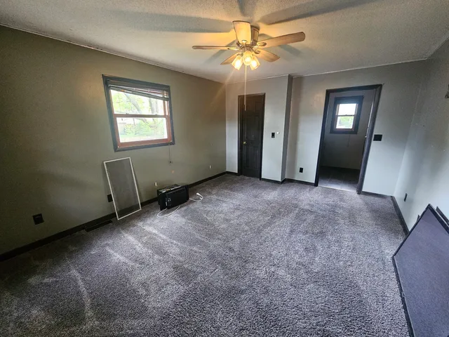 a view of a room with a hanging light and hardwood floor