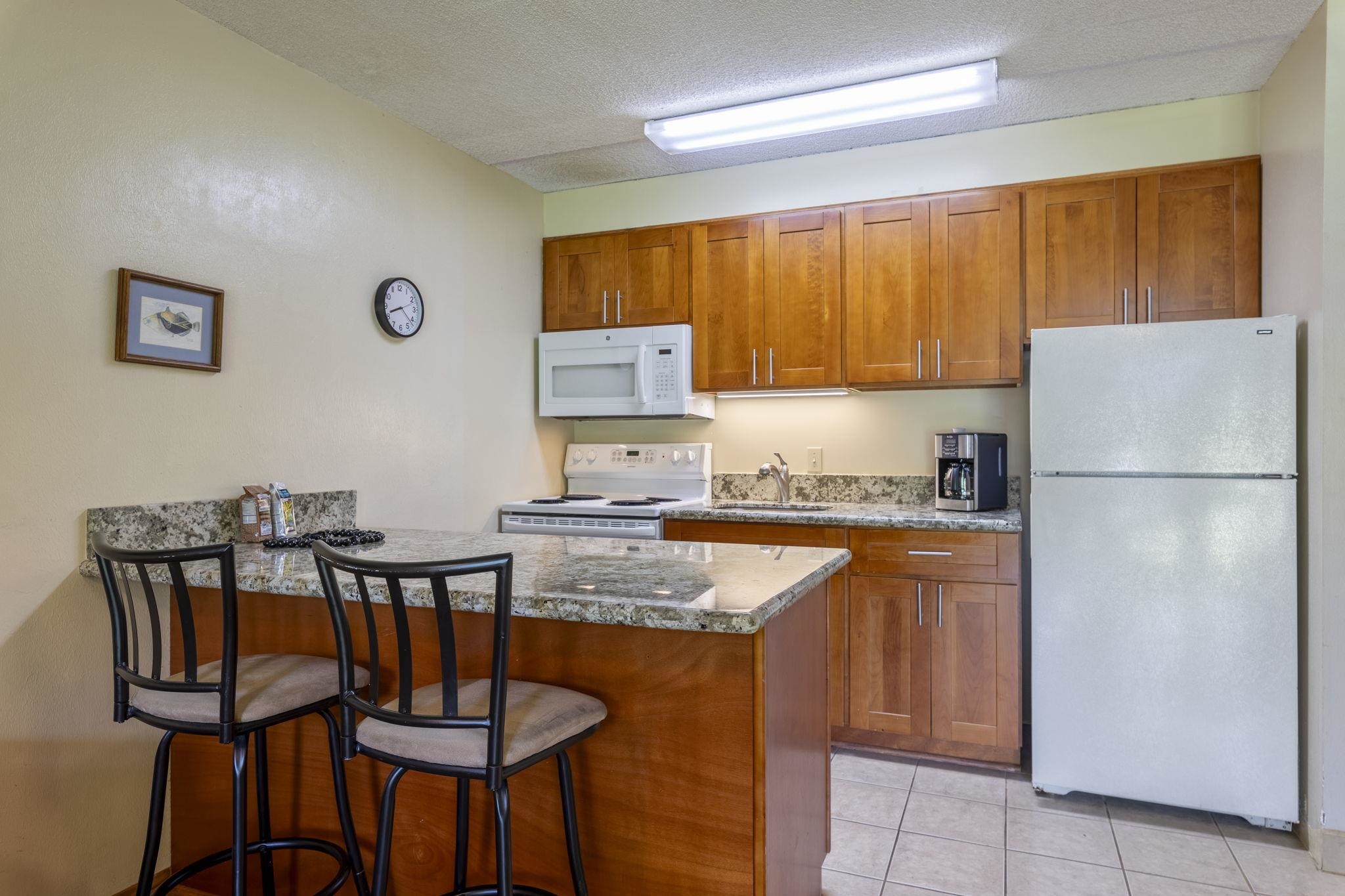 2495 South Kihei Road, Unit 120 Kihei, HI 96753 - Photo 9 of 40 a kitchen with stainless steel appliances granite countertop a refrigerator and a stove top oven