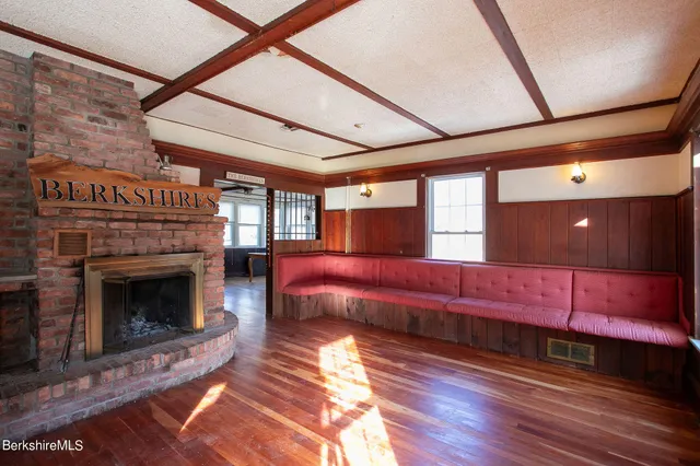 a view of a white house next to a yard with potted plants and big trees
