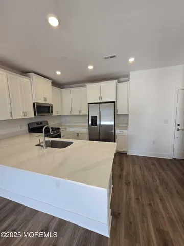 a kitchen with stainless steel appliances granite countertop a sink a stove a refrigerator a microwave oven with cabinets and wooden floor