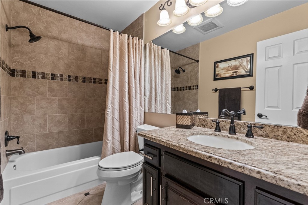 20344 Calhaven Drive Saugus, CA 91390 - Photo 41 of 70 a bathroom with a granite countertop sink a toilet a mirror a bathtub and shower