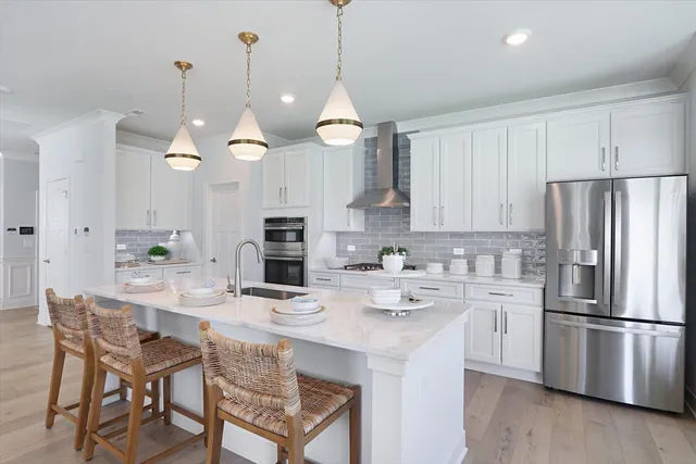 a kitchen with stainless steel appliances a dining table chairs and a refrigerator
