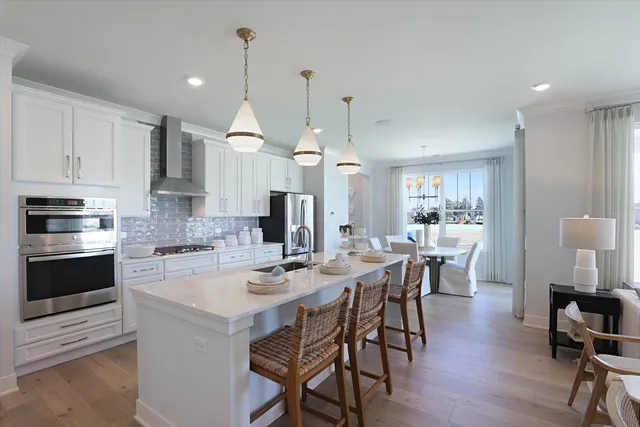 a kitchen with a dining table chairs stainless steel appliances and cabinets
