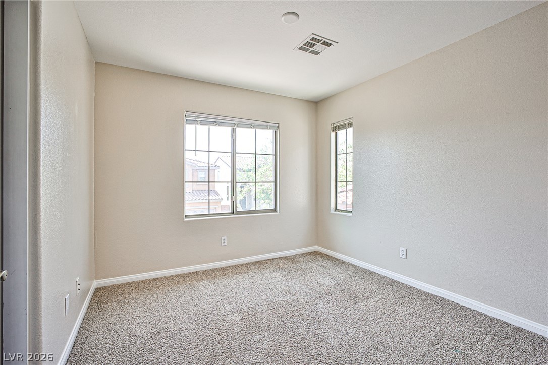 8022 Diamond Gorge Road Las Vegas, NV 89178 - Photo 25 of 37 Multi-pane windows illuminate a neutral carpeted secondary bedroom with smooth walls.