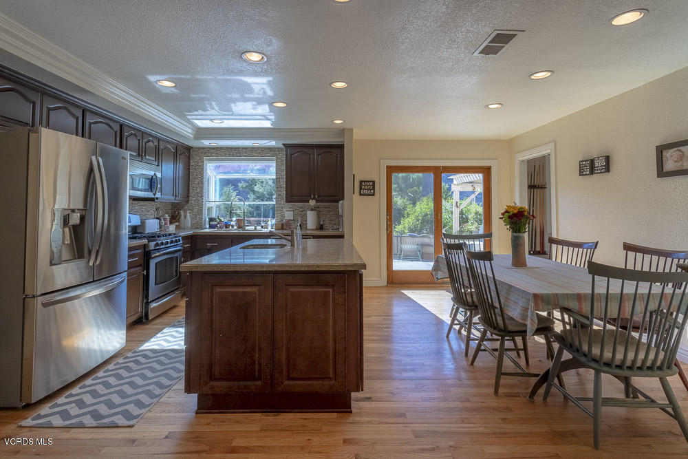 1168 Rambling Road Simi Valley, CA 93065 - Photo 13 of 45 a kitchen with stainless steel appliances granite countertop a refrigerator a stove a sink a dining table and chairs with wooden floor