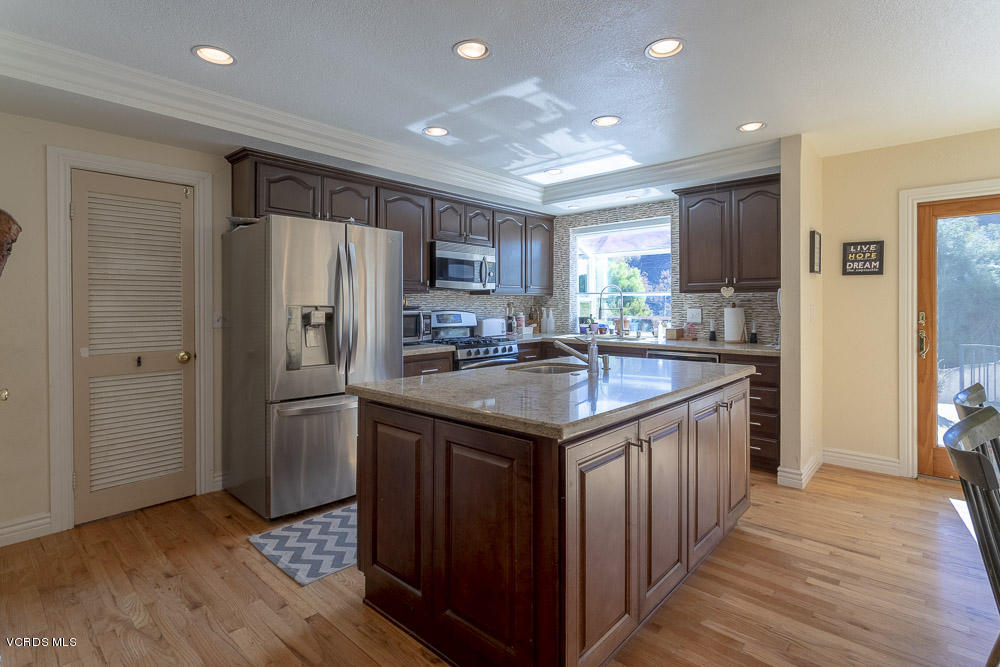 1168 Rambling Road Simi Valley, CA 93065 - Photo 9 of 45 a kitchen with stainless steel appliances granite countertop a refrigerator a sink dishwasher a stove with wooden cabinets and floor