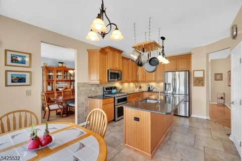 a kitchen with stainless steel appliances granite countertop a sink a stove and a dining table