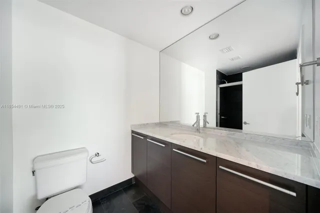 a bathroom with a granite countertop sink a toilet and a mirror