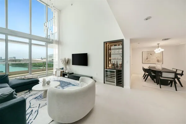 a living room with furniture a flat screen tv and a large window