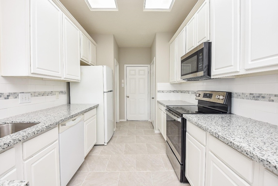 5619 Stonecloud Lane Katy, TX 77494 - Photo 13 of 31 a kitchen with stainless steel appliances granite countertop white cabinets and a sink