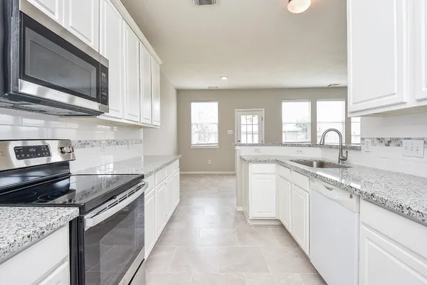 a large kitchen with stainless steel appliances granite countertop a sink stove and microwave