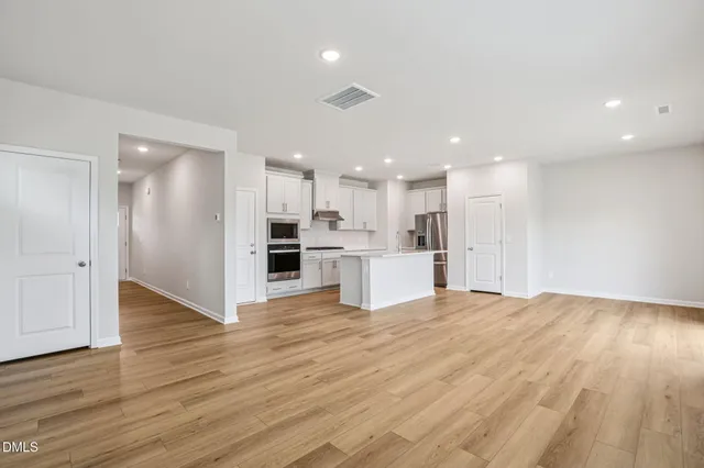 a view of kitchen with kitchen island stainless steel appliances wooden floor and window
