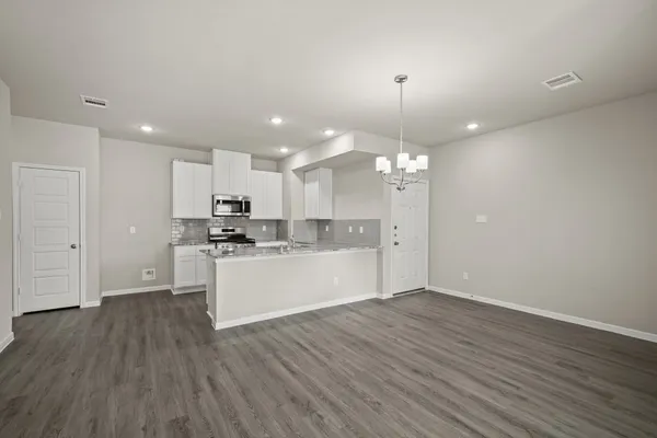a view of a kitchen with kitchen island wooden floor appliances and a window
