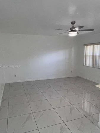 a view of an empty room with a ceiling fan and window