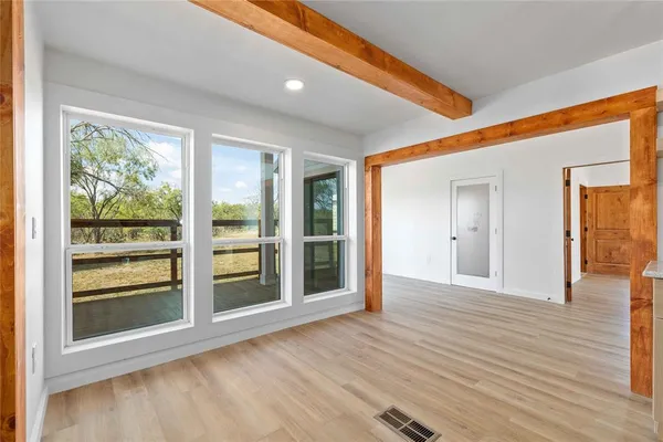 a view of an empty room with a window and wooden floor
