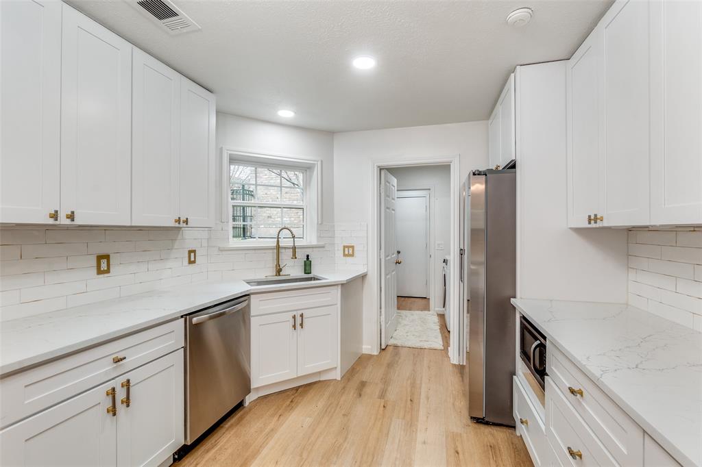 9130 Valley Chapel Lane Dallas, TX 75220 - Photo 16 of 39 a kitchen with a sink dishwasher a refrigerator and white cabinets with wooden floor