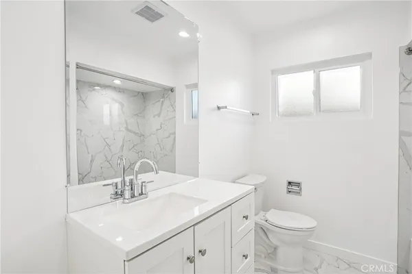 a bathroom with a sink a toilet a mirror and vanity