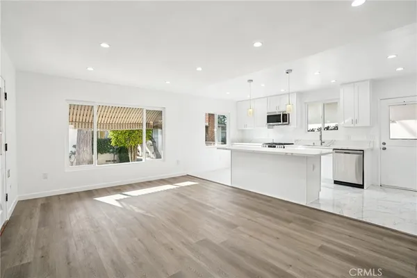 a large white kitchen with wooden floors and white cabinets