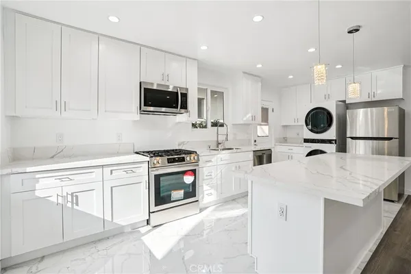 a kitchen with stainless steel appliances kitchen island granite countertop a sink and a stove