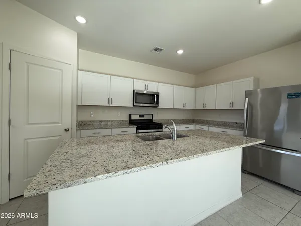 a kitchen with stainless steel appliances granite countertop a sink a stove and a refrigerator with wooden floor