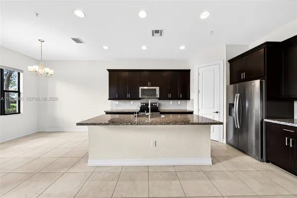 a large kitchen with a counter top a refrigerator and a sink
